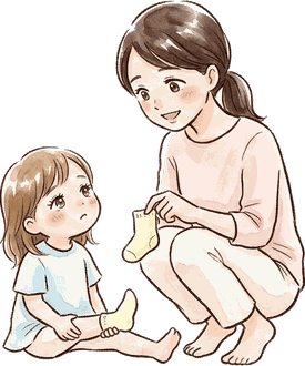 床に座った上の子が、靴下をはかせてほしそうにママを見上げている
