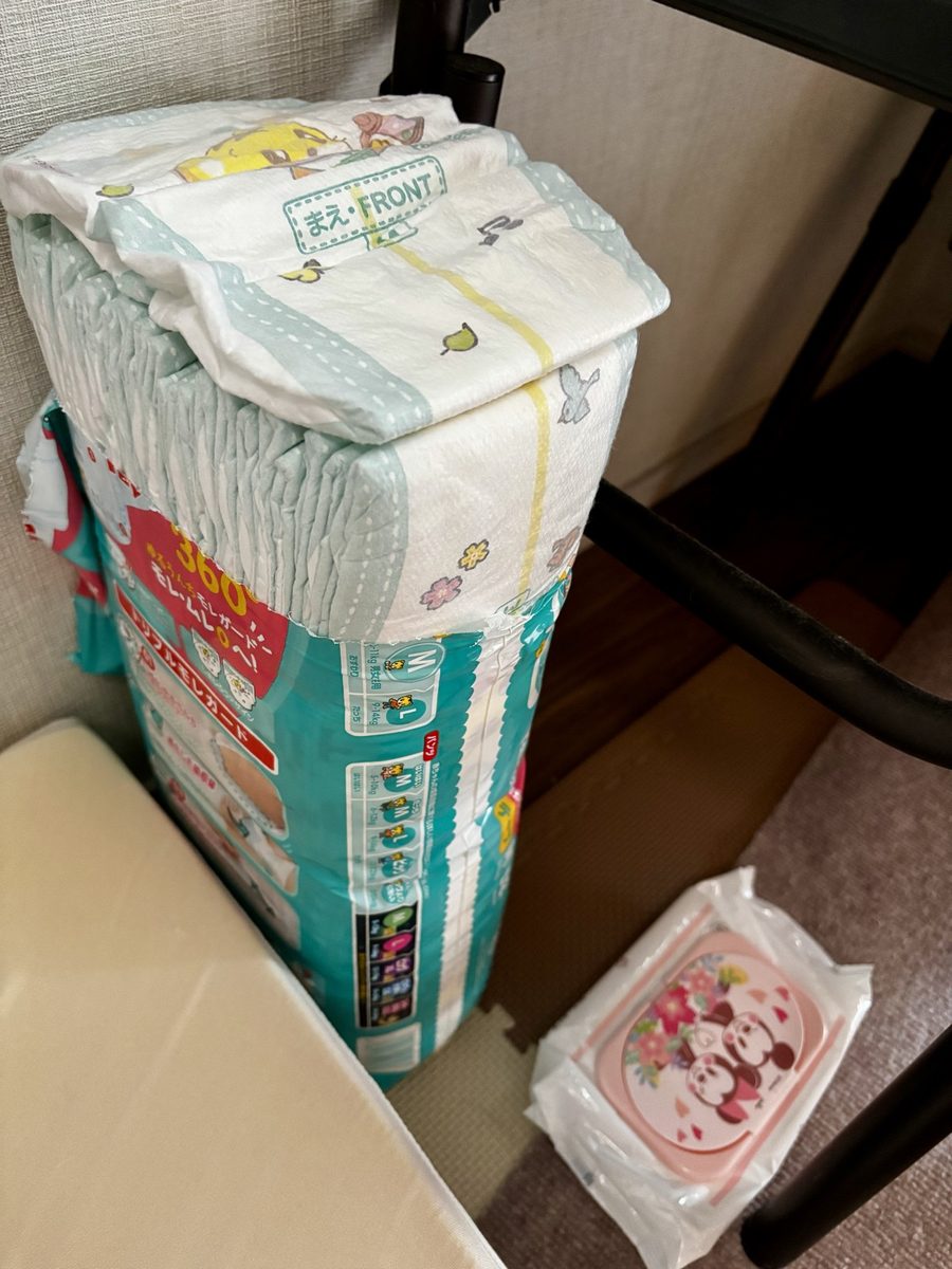 ベビーベッドのそばに置いてあるパンパースMサイズのおむつの袋とおしりふき